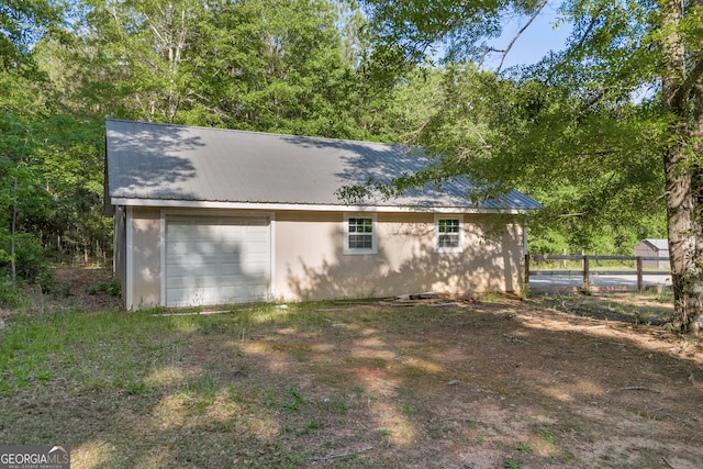 view of outbuilding featuring fence, an outdoor structure, and a garage