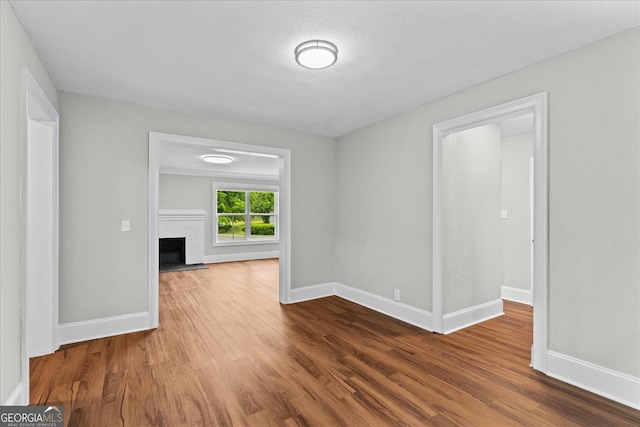 spare room with a brick fireplace, baseboards, and wood finished floors