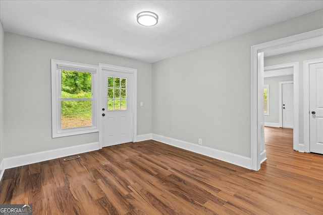 interior space featuring baseboards, wood finished floors, and visible vents