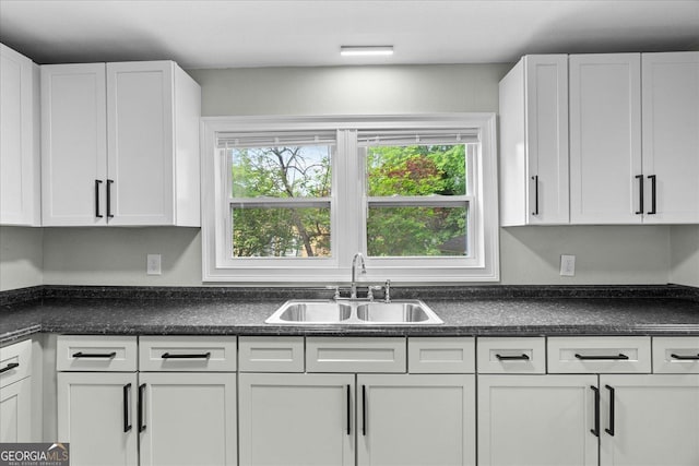 kitchen featuring a sink, white cabinets, a healthy amount of sunlight, and dark countertops