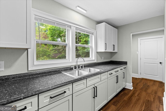 kitchen with a sink, baseboards, white cabinets, and dark wood-type flooring