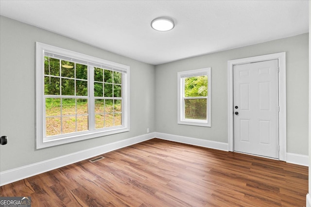 spare room with baseboards, wood finished floors, a healthy amount of sunlight, and visible vents