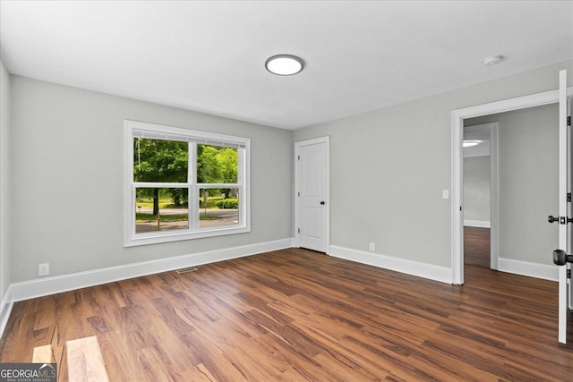 unfurnished bedroom with baseboards, visible vents, and dark wood-type flooring