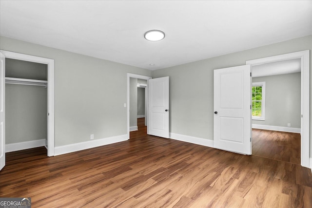 unfurnished bedroom featuring baseboards, a closet, and wood finished floors