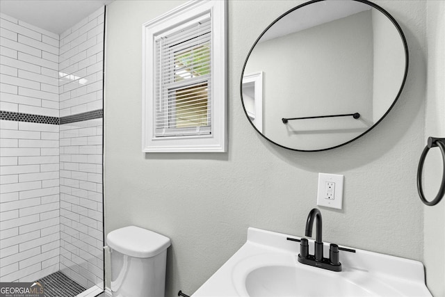 full bath featuring a sink, toilet, and tiled shower