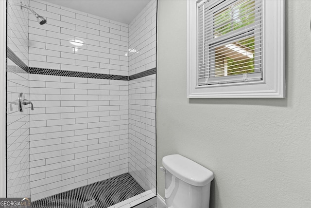 bathroom featuring a textured wall, toilet, and a shower stall