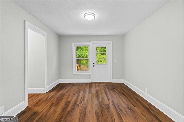 interior space featuring baseboards, dark wood finished floors, and a textured ceiling