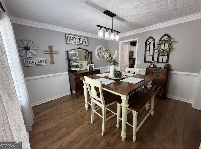 dining area featuring dark wood-style flooring, wainscoting, a textured ceiling, and crown molding