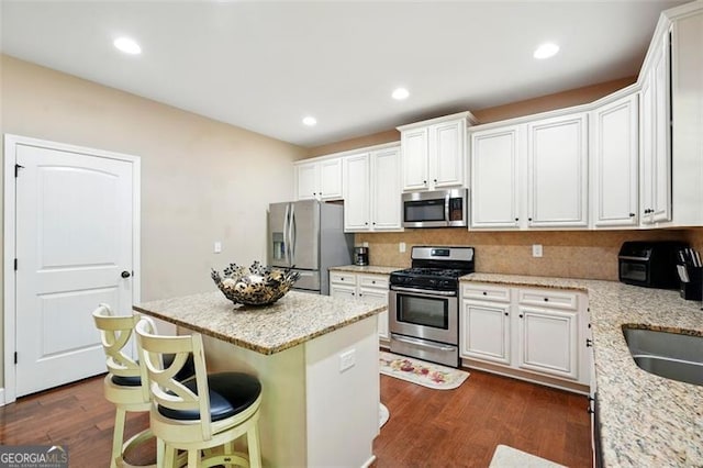 245 Tapestry Dr, Mcdonough, GA 30252 - kitchen featuring white cabinets, appliances with stainless steel finishes, light stone counters, a center island, and dark wood-type flooring