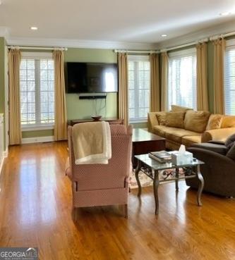 living room with crown molding, baseboards, recessed lighting, and wood finished floors