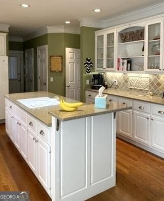 kitchen with a kitchen island, white cabinetry, ornamental molding, and dark wood-type flooring