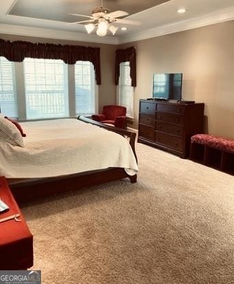 carpeted bedroom with recessed lighting, ornamental molding, ceiling fan, and a tray ceiling
