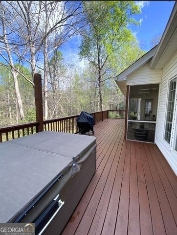 wooden deck featuring a covered hot tub and a sunroom