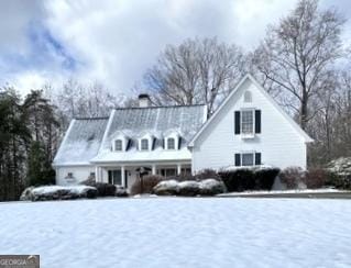 snow covered property featuring covered porch and a chimney