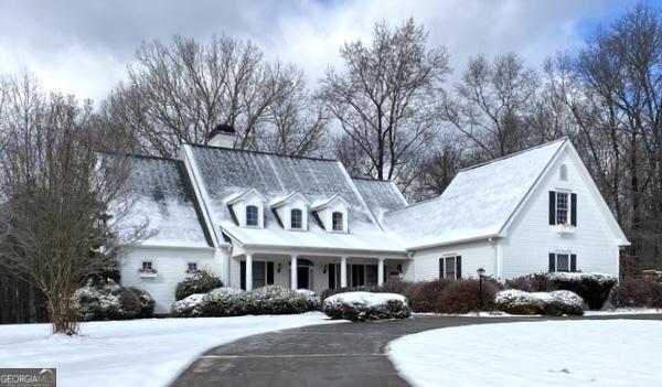 cape cod house with covered porch and a chimney