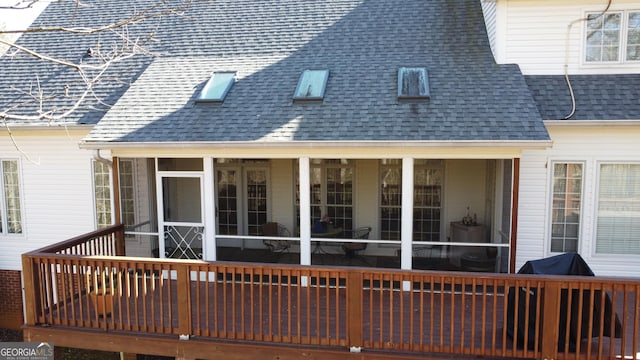 back of property with a shingled roof and a sunroom