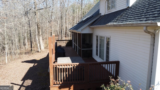 view of side of property featuring a wooden deck and roof with shingles