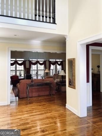 foyer entrance with ornamental molding, wood finished floors, and a towering ceiling