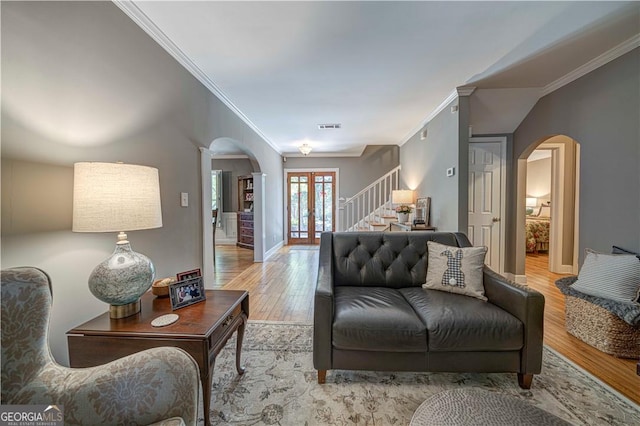 living room featuring arched walkways, ornamental molding, stairway, wood finished floors, and decorative columns