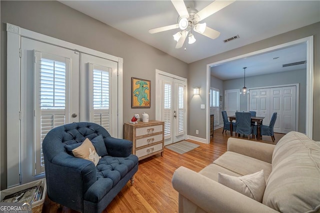 living area with french doors, light wood finished floors, a ceiling fan, and baseboards