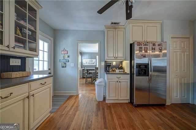 kitchen featuring stainless steel fridge, cream cabinets, ceiling fan, dark wood-style floors, and dark countertops