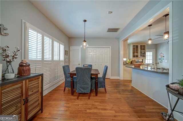 dining space with wood finished floors, a ceiling fan, and baseboards