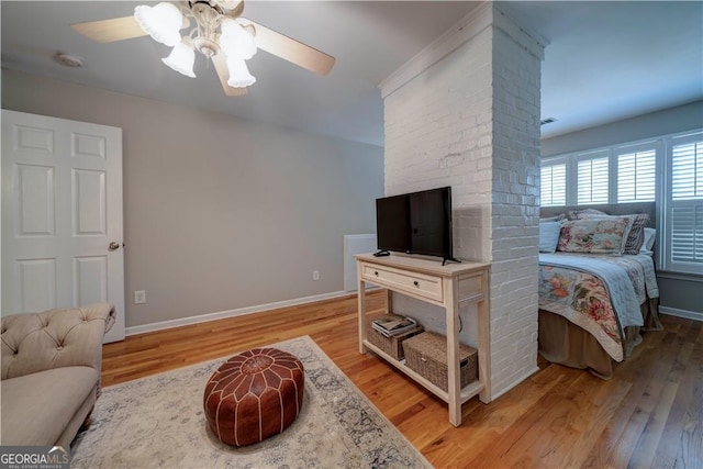 living area with wood finished floors, a ceiling fan, and baseboards