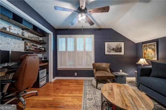 office space featuring ceiling fan, wood finished floors, baseboards, and vaulted ceiling
