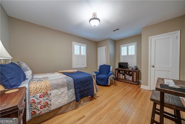 bedroom featuring multiple windows, hardwood / wood-style flooring, and baseboards