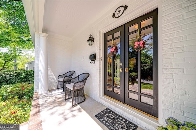 property entrance with a porch, brick siding, and french doors