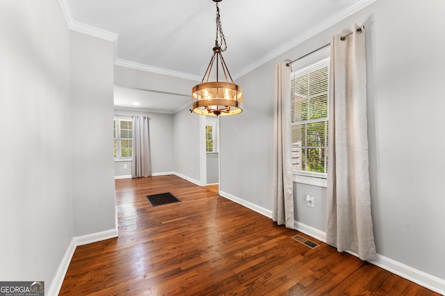 unfurnished dining area with visible vents, wood finished floors, baseboards, a notable chandelier, and ornamental molding