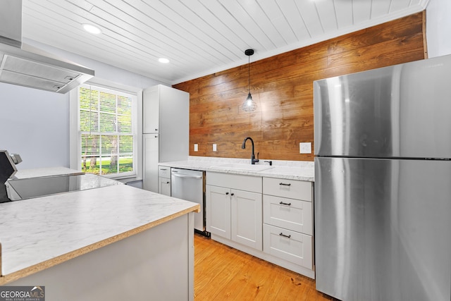 kitchen featuring wooden walls, appliances with stainless steel finishes, a sink, light wood finished floors, and recessed lighting