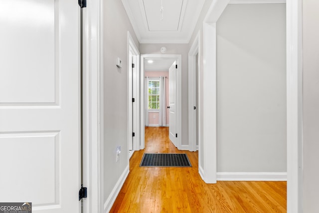 hall featuring crown molding, attic access, baseboards, light wood-type flooring, and visible vents