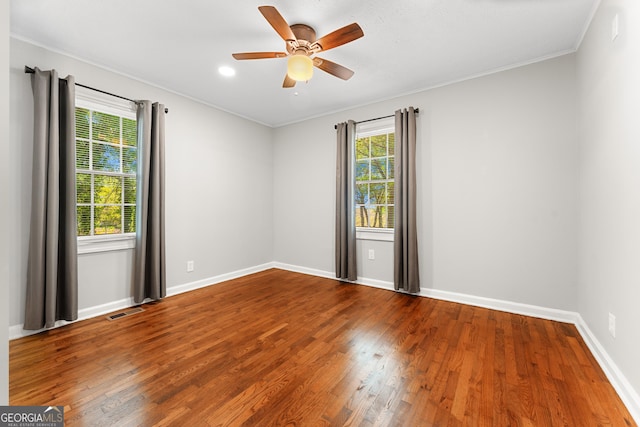 empty room featuring visible vents, ornamental molding, wood finished floors, baseboards, and ceiling fan