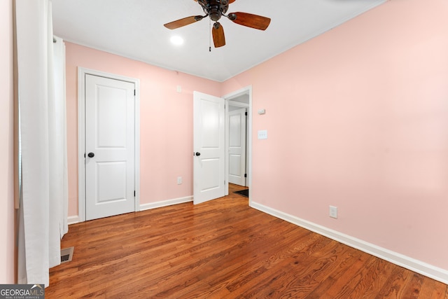 unfurnished bedroom with baseboards, ceiling fan, wood finished floors, and visible vents