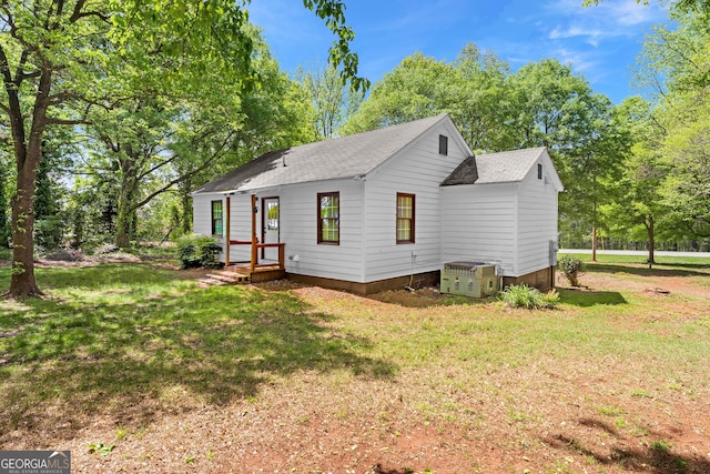 rear view of house with roof with shingles and a yard