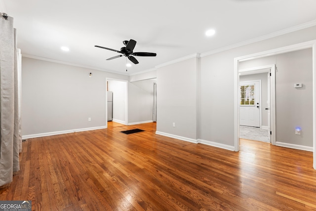 interior space with crown molding, a ceiling fan, baseboards, and wood finished floors