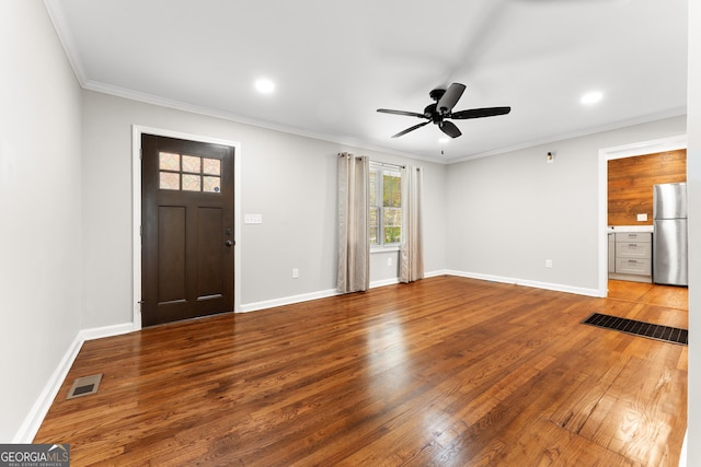 foyer entrance with ceiling fan, visible vents, crown molding, wood finished floors, and baseboards
