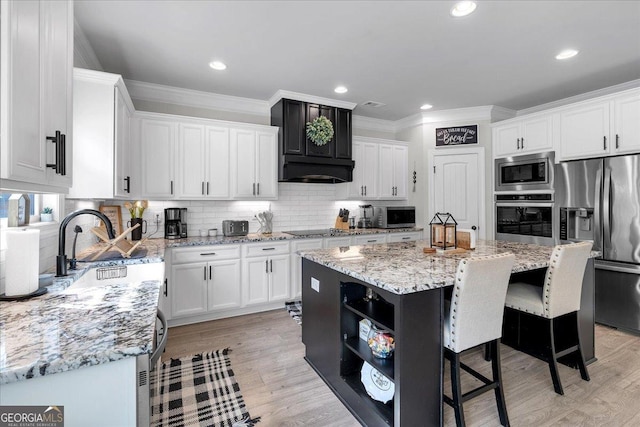 4575 Birch Way, Loganville, GA 30052 - kitchen with appliances with stainless steel finishes, a kitchen island, a breakfast bar, white cabinets, and light stone counters