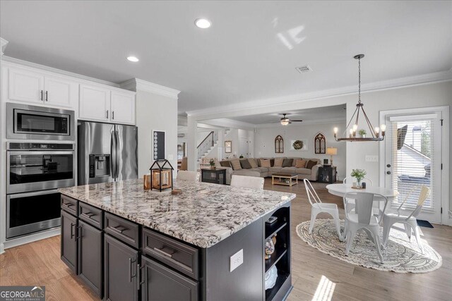 4575 Birch Way, Loganville, GA 30052 - kitchen featuring appliances with stainless steel finishes, crown molding, white cabinetry, a kitchen island, and light stone countertops