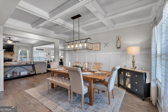 4575 Birch Way, Loganville, GA 30052 - dining room with a chandelier, beam ceiling, a ceiling fan, a fireplace, and wood finished floors