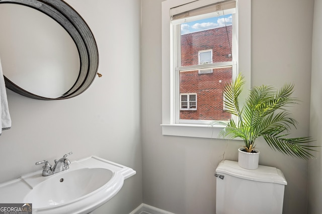 half bath with a sink, toilet, and baseboards