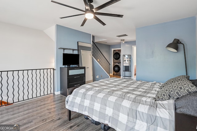 bedroom featuring estacked washer and dryer, wood finished floors, and ceiling fan
