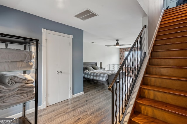 stairs featuring wood finished floors, ceiling fan, and baseboards