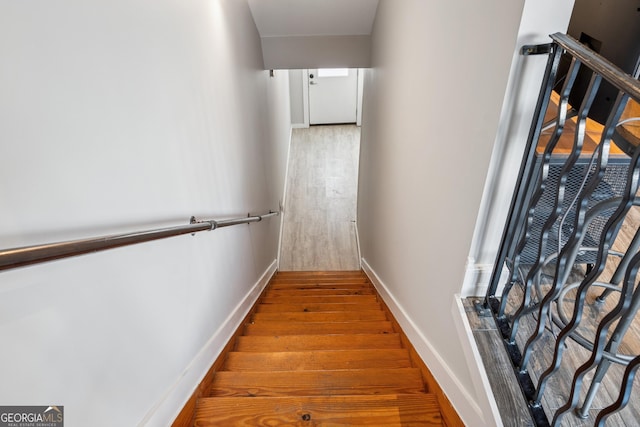 hall with wood finished floors, baseboards, and stairs