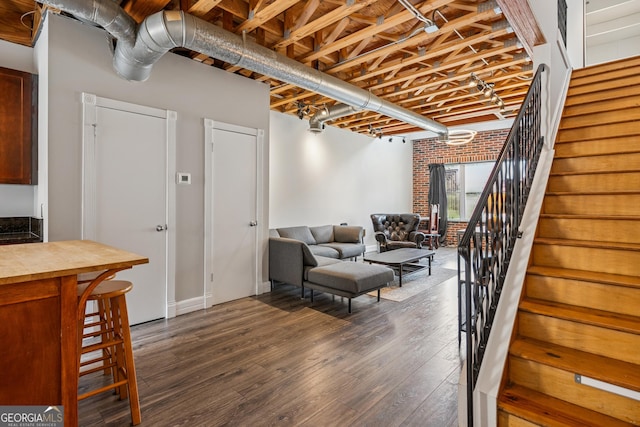 living room with stairs, dark wood-type flooring, and baseboards