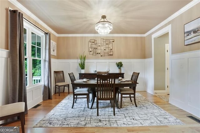 4383 Capstone Ct NE, Roswell, GA 30075 - dining room with a decorative wall, a chandelier, wood finished floors, wainscoting, and ornamental molding