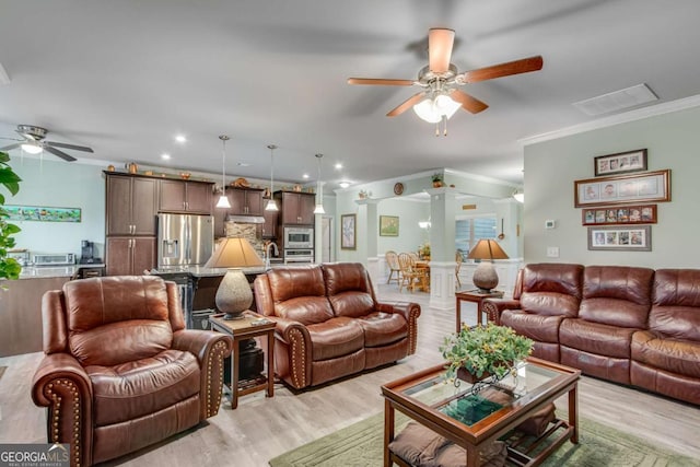 living room featuring a ceiling fan, ornamental molding, visible vents, and light wood-type flooring