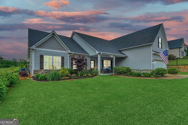 view of front facade with a lawn, roof with shingles, and an attached garage
