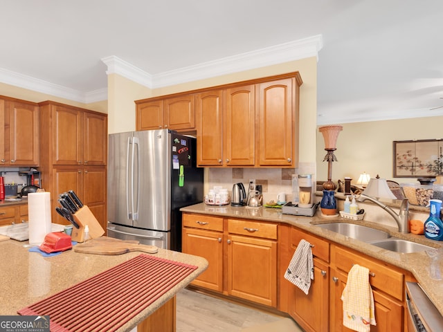 kitchen featuring a sink, freestanding refrigerator, dishwasher, crown molding, and backsplash
